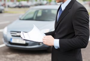 man looking over documents. papers in hand. man reviewing if he wants to make purchase on car.