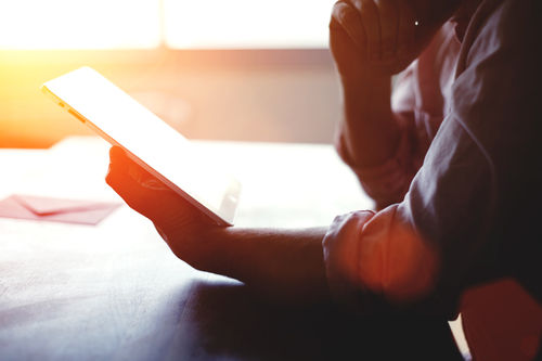 man debating online, if he should make a purchase, has iPad in hands.