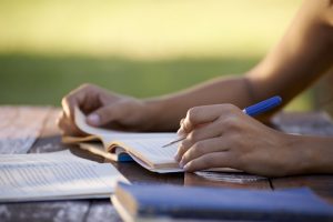Young women and education, close up of hands of girl studying for college exam in park. Side view, copy space