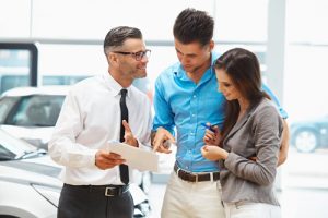 Young Couple Signing a Contract in Car Showroom.